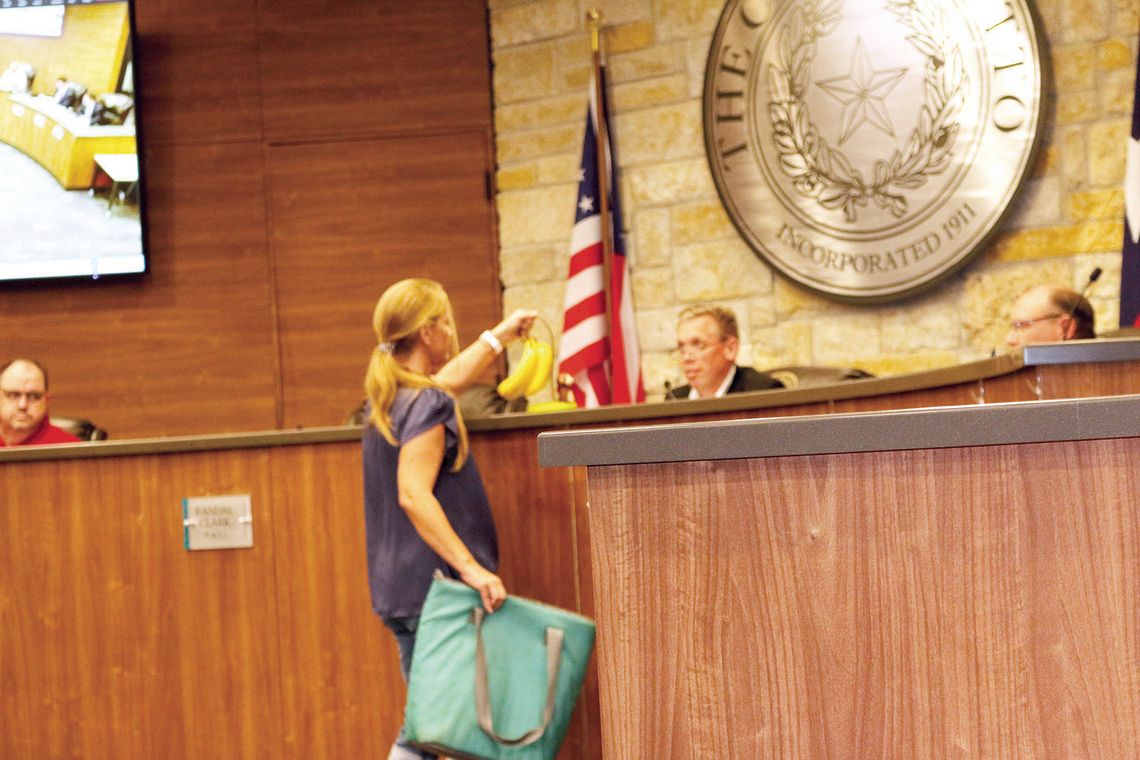 Hutto resident Nicole Calderon presents the mayor with bananas to illustrate her view of city council’s behavior. Photo by Edie Zuvanich