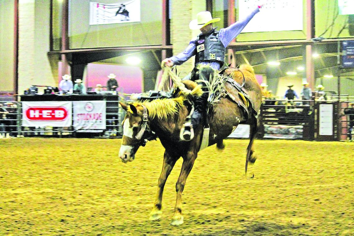 Rodeo contestant competes in saddle bronc riding event in a previous rodeo. In the contest, the participant must stay on the horse for eight seconds without touching the animal with their free hand. Photo from Staff Files