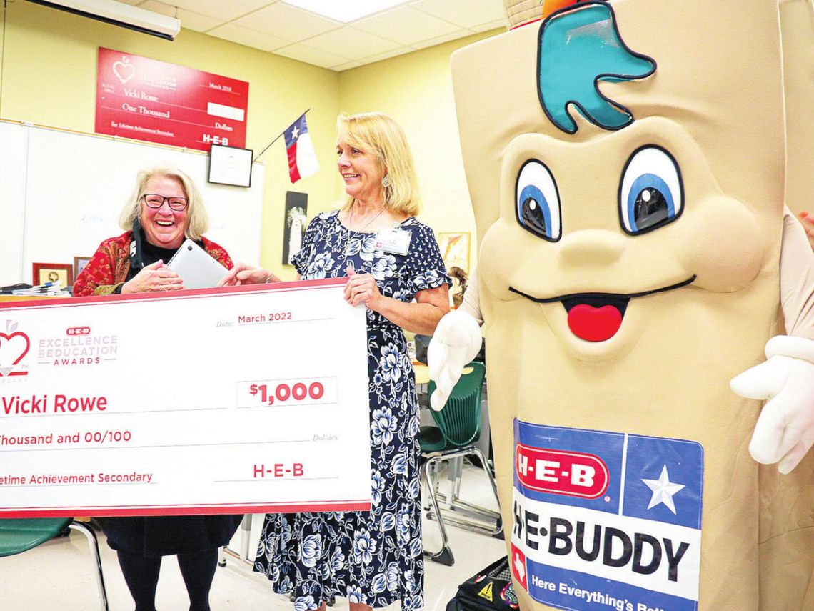 Taylor High School teacher Vicki Rowe is surprised with the HEB Excellence Award by HEB representatives Jill Reynolds and H-E-BUDDY. Photo by Ryan Newsom