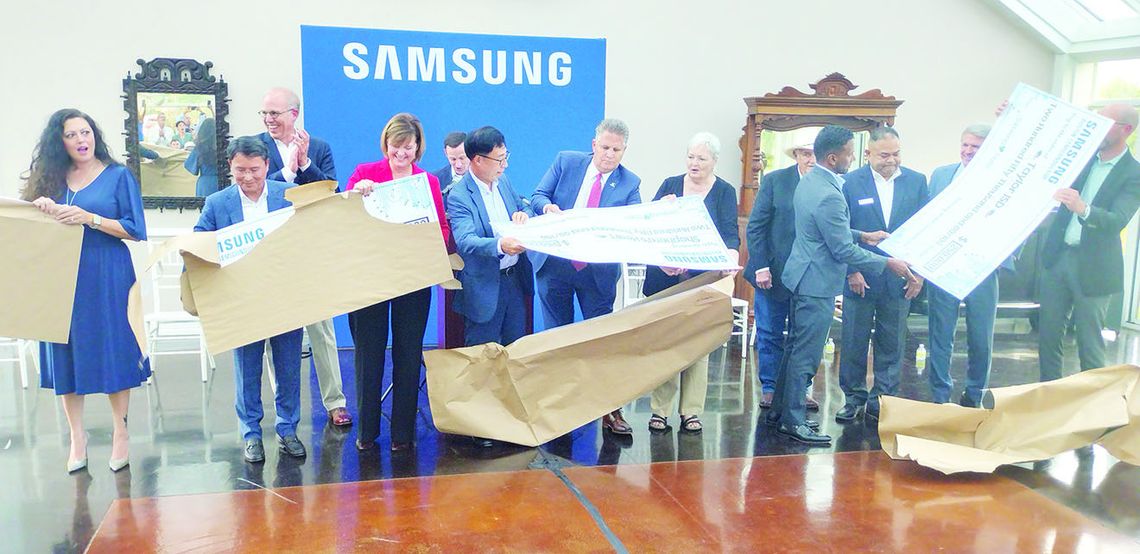 Members of local organizations unwrap giant $250,000 checks at a Samsung announcement event. Photo by Jason Hennington