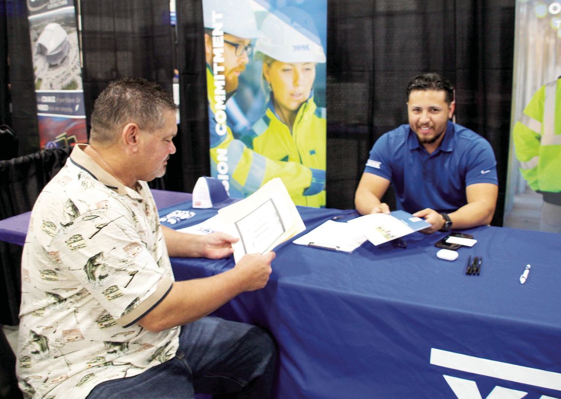 Joshua Mena, a recruiter for Yates Construction, chats with job seeker Edward Betak Jr. a Sept. 1 job fair hosted by Samsung Austin Semiconductor at the Williamson County Expo Center Photo by Nicole Lessin