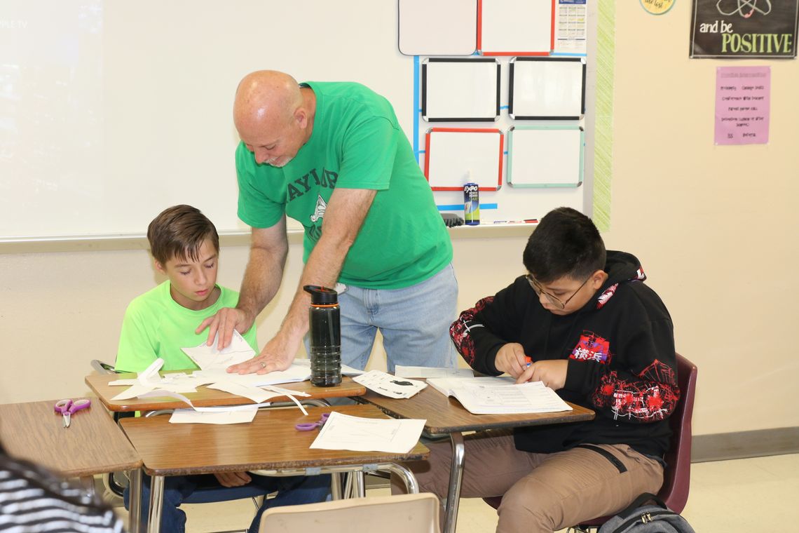 Taylor Middle School science teacher Briana Zana assists Kayden Leland (left) and Christopher Barzola with setting up their Interactive Science Notebooks. Photos by Tim Crow