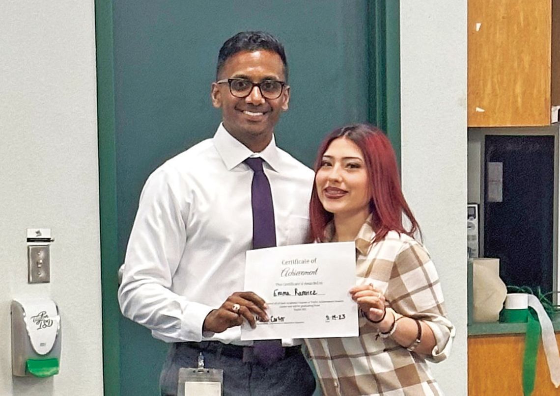 Taylor ISD Superintendent Devin Padavil (left) presents Emma Ramirez with her certificate of completion.