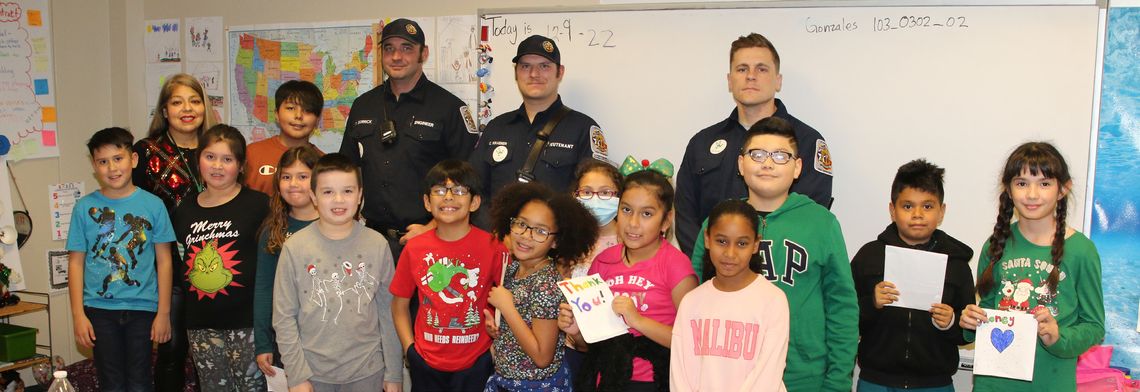 Students in Teresa Gonzales’ third grade class at Naomi Pasemann Elementary present the Taylor Fire Department with a donation for the Red Santa Program. The money was used to purchase food and presents for several Taylor Families. Photo by Tim Crow