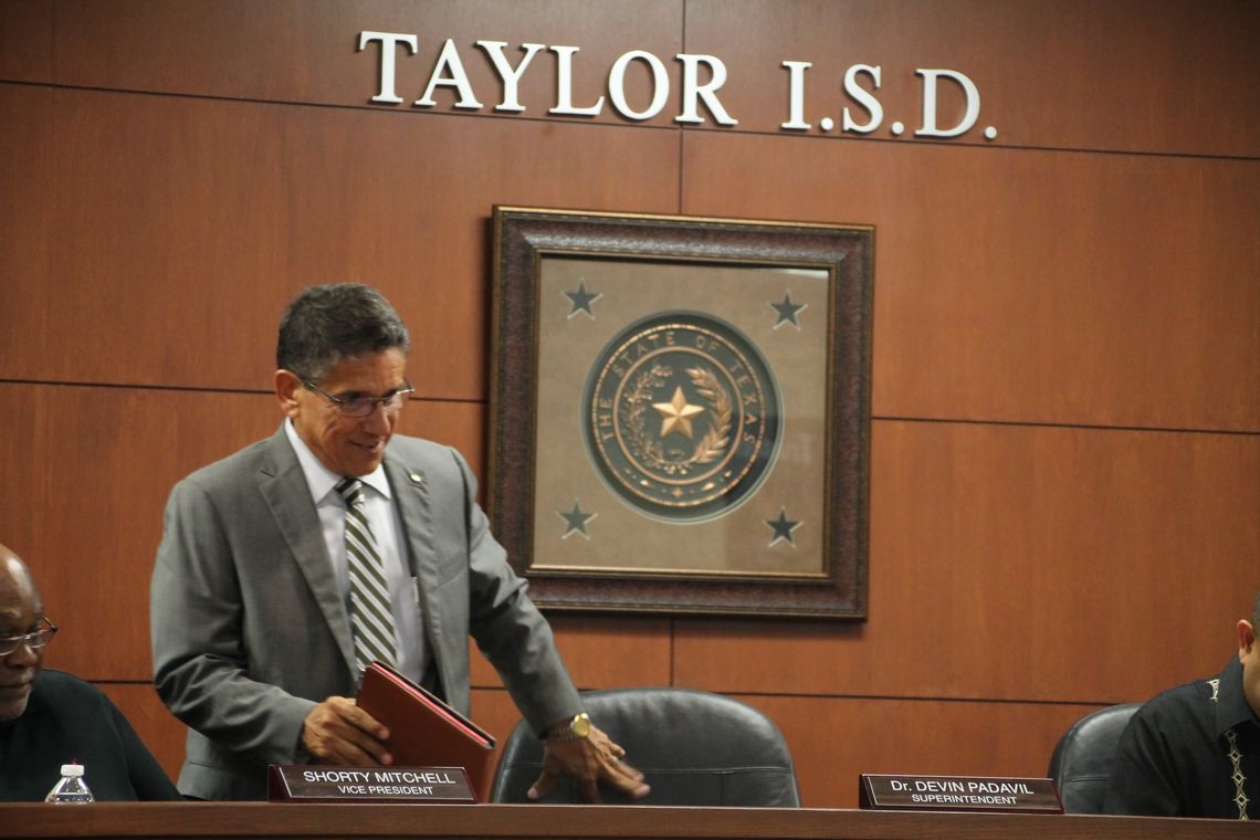 Steve Flores, Taylor Independent School District's new interim superintendent, ceremoniously joins the trustees at the school board meeting. Photo by Hunter Dworaczyk.