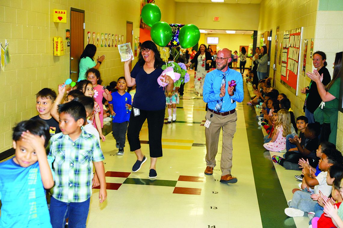 T. H. Johnson Elementary students and staff celebrate their Teacher of the Year, Lucia Arellano, in a parade around the campus. Arellano is accompanied by her class and by Principal Andy Basche. Photo by Tim Crow