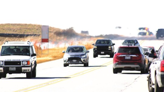 Left: The Balcones Resources building on Chandler Road caught on fire Friday afternoon. Above: Cars carefully travel on Chandler Road to avoid fire that spread out to the highway. Photos by Jason Hennington