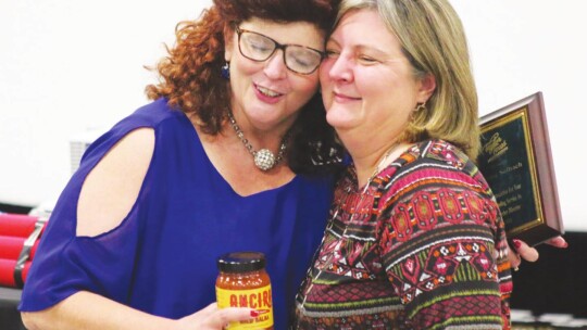 Chamber President Tia Stone (left) hugs outgoing board member Denise Solbach at the chamber banquet.