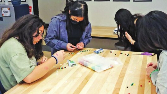 Students come up with creative ideas using beads and other items to make unity bracelets.