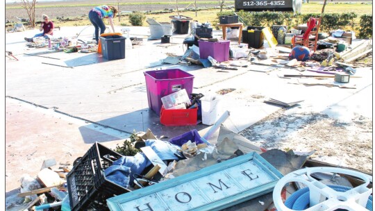 Family members of Dean and Sharrion Threadgill help clean up rubble from their home outside of Granger March 24 after a tornado demolished their property three days earlier. Photo by Fernando Castro