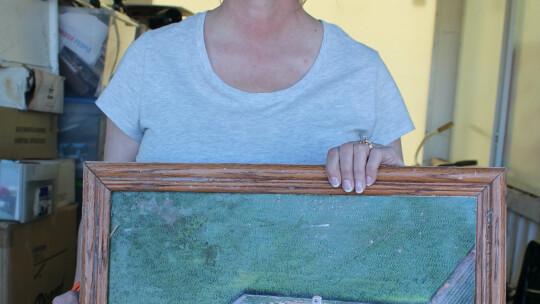 Sharrion Threadgill shows an aerial photo of what their Granger-area home looked like as she stand of inside a trailer filled with some of what was recovered as of March 24