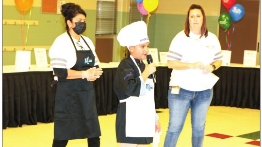 Christian Parada-Ortiz answers questions from the judges as they sample his entry, pupusas. Watching are his mentor, Yesenia Sanchez, Taylor High School assistant cafeteria manager; and Taylor ISD Child Nutrition Director Lindsey Gage.