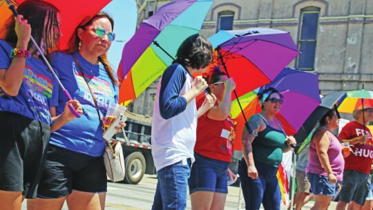 Members of the Parasol Patrol use rainbow umbrellas to shield people from protesters, but to also stay shaded from the sun.