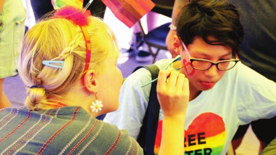 Selah Valerio (right) gets a heart painted on her face by Gwen Richards at the Taylor PRIDE festival Saturday afternoon.