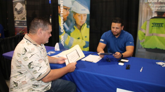 Joshua Mena, a recruiter for Yates Construction, chats with job seeker Edward Betak Jr., at the Sept. 1 fair.