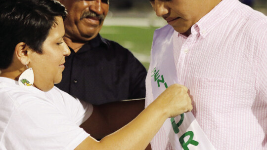 Maria Guerrero (left) helps homecoming prince Miguel Ruiz with his sash. Ruiz was escorted by Guerrero and Jose Ruiz. Photo by Jason Hennington