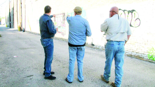 (left to right) Public Works Director Jim Gray speaks with Arts Committee Chair Richard Stone and Street Supervisor Brett Bachmeyer Sept. 30 about which sections of the wall to cover with white paint in Potter's Alley. Photo by Nicole Lessin