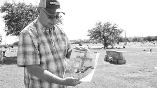 Felix Pavlicek shows a picture of the wooden cross and flag that he had to remove from the grave of his friend, Denise Richter, at the city cemetery. A city law prohibits most memorials. Photos by Nicole Lessin