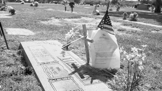 A violation letter hangs on a small metal cross Oct. 6 at the city cemetery. According to a Taylor ordinance, such items are not allowed.