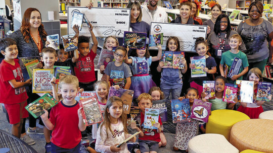 Sharon Case and students at Kerley Elementary School show off books as Case accepts two grants for $4,806 each to help students “Step Into a Book.”