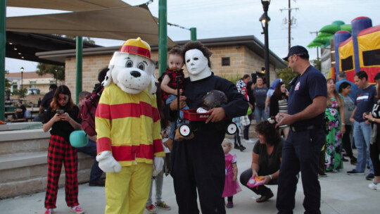 Sparky the Fire dog poses with Ricky Sanchez, dressed as Mike Myers from Halloween and his son Kayden Sanchez, 2, dressed as Joe Dirt.