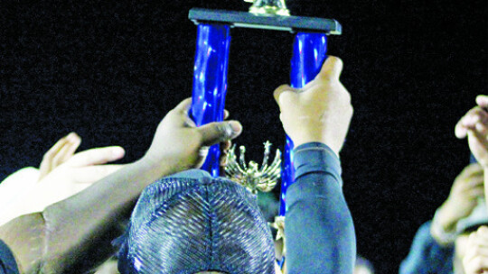 Youth Ducks players and coaches holding up the trophy together.