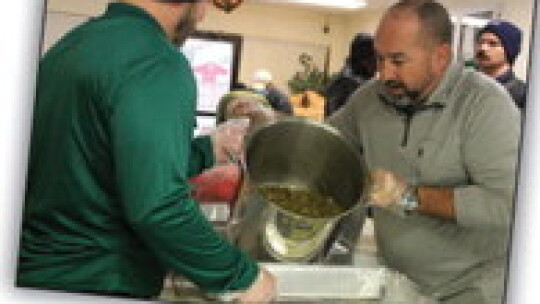 Manager Brian LaBorde pours a heavy tray of green beans into a catering tray with District 4 Councilman Robert Garcia Nov. 19 at Zion Chapel Missionary Baptist Church. urch.