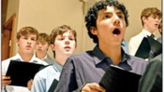 High school students Brady Altman, Kaedin Hamner and Jose Hengst sing from the balcony during the Christmas choir concert at St. Mary’s Catholic School.