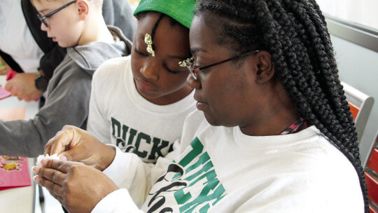 (From left) Unitey Fields, 8, learns how to make an ornament with mom Courtney Fields, the cheer coordinator for the Taylor Youth Ducks varsity football team.