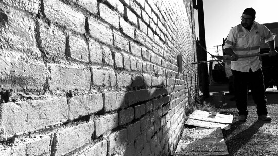 Taylor public works staffer Chris Gonzales applies a new coat of paint Sept. 30 to the wall on the north side of Potter’s Alley. Photo by Nicole Lessin