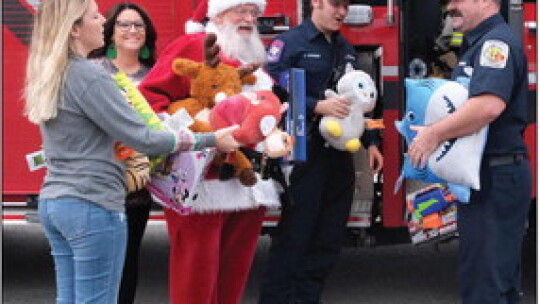 – (From left) Rena Wade, Briana Ford and Santa help Taylor firefighters Cody Kraemer and Zach Reeves load toys into the fire truck. Photos courtesy of Rena Unique Photography