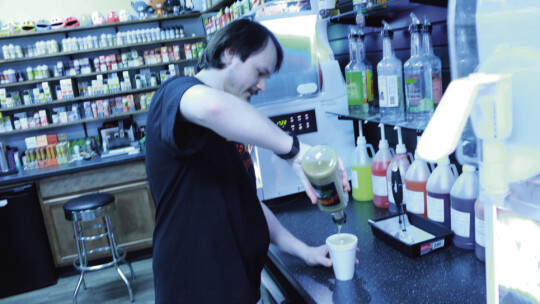 Top: Manager Justice King pour s a f rozen White Russian daiquiri. Above: King adds a custom shot of liqueur to a frozen daiquiri.