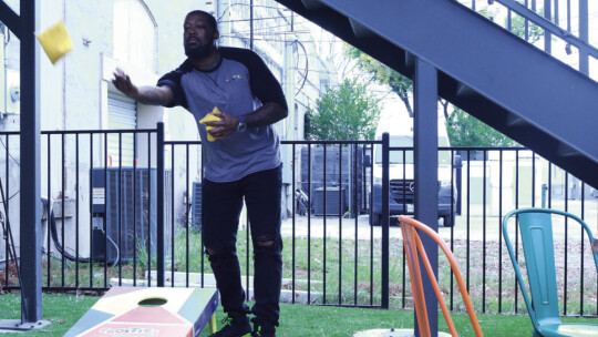 Frosties Owner Roshon Alfred shows off his cornhole skills on the patio.