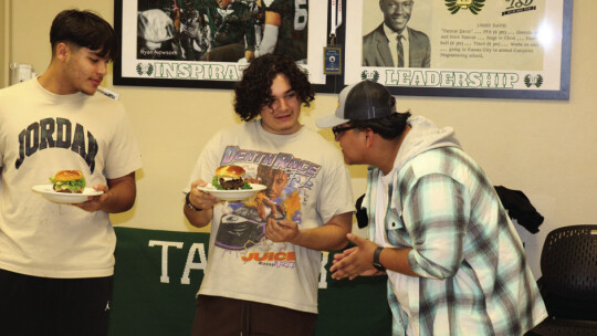 Student Chef Tristan Rodriguez asks for feedback from culinary classmates Nick Walker and Gonzalo Cruz before presenting his burger to the judges.