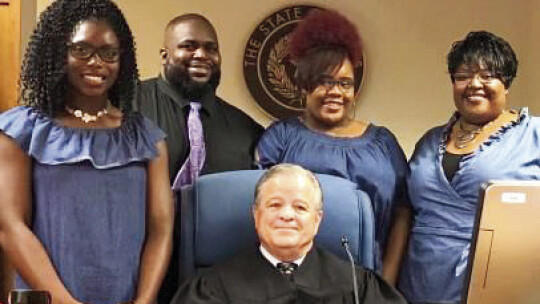 (From left) Quincy Griffin surrounded by daughters Lakaysha Davis-Griffin and Deovionne Griffin and wife Shanaye Griffin during the adoption ceremony June 21, 2018. Courtesy photo