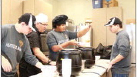 Student Curtis Chelf, chef Said Farraje, and students Donovan Steward and Kaden Long work together to fill the soup orders.