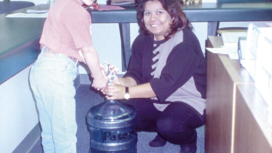 Kristyne Baran, a student at Pasemann in 1998-99, deposits her donation to the Pasemann Pennies fund with the assistance of then receptionist, Bernice Sanchez. Photo by Tim Crow