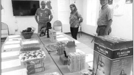 At the Coupland Volunteer Fire Department silent auction, (from left) Peter Wabbel, Dana Smith, and Danny Smith look at a selection of items. Photo by Susan Garry