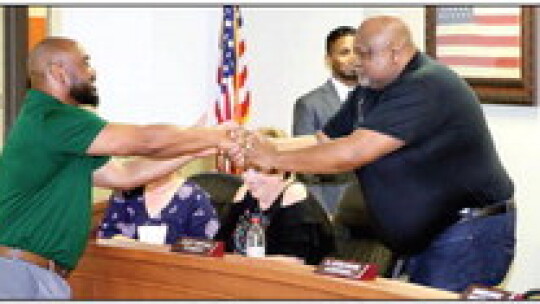 Earven Flowers (left) is congratulated by Taylor ISD school board vice president Shorty Mitchell after the announcement of Flowers as new athletic director and head football coach. Photos by Jason Hennington