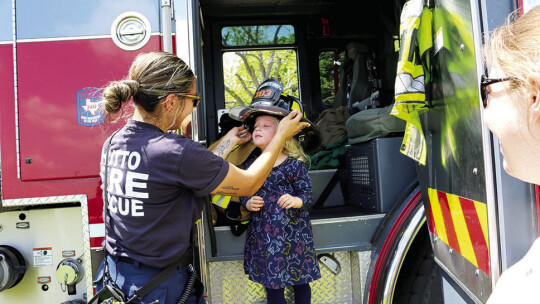 Hutto Fire Rescue firefighter Stephanie Anaya helps Amelia (age 3) try on a helmet.