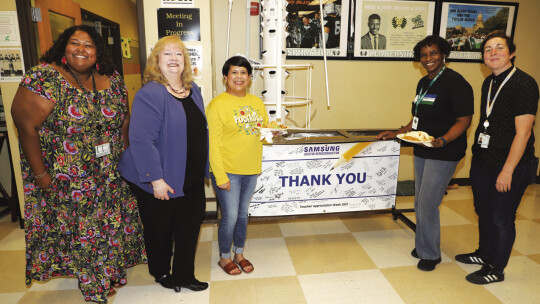 Michele Glaze and Wesley King present a signed banner of appreciation from Samsung Austin Semiconductor to the Taylor High School staff. From left are Racquel Vrana, Michele Glaze, Estefanie Adame, Selina Shaw and Wesley King. Photo by Tim Crow