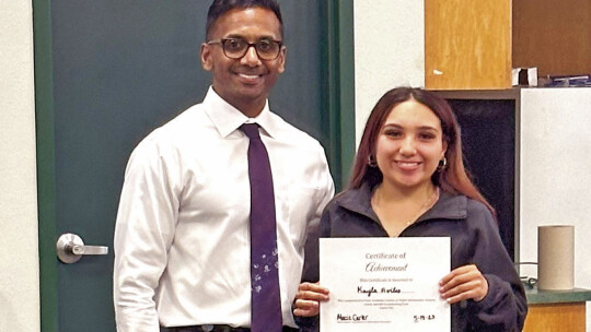 Kayla Aviles (right) smiles after Devin Padavil, superintendent, presents her with a certificate of completion.