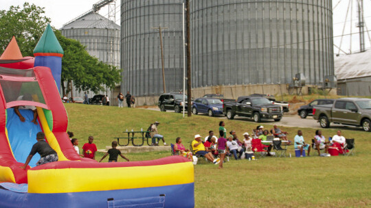 Community members gather at the bottom of a slope in front of blues band Jabo and the Old Dogs and next to a bouncy house for kids at the Juneteenth celebration Monday, June 19, hosted by Southside Community Engagement. Photo by Grace Horvath