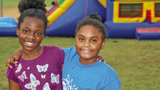 Jurnii Wilson (left) and Praylah Winn pose in front of the bouncy house Monday evening at Southside Community Engagement Juneteenth celebration. Photo by Grace Horvath