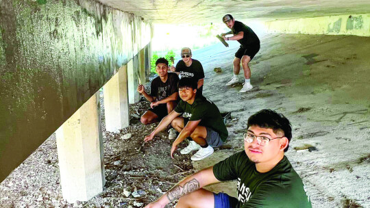 A group of volunteers pose while painting over graffiti. The interns also picked up trash and painted hand rails.