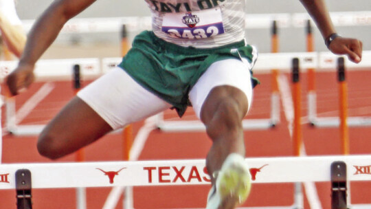 Taylor High School boys varsity track and field standout Jarvis Anderson clears a hurdle on May 11 during the 300-meter hurdles event en route to a gold medal at the Class 4A UIL Track and Field Championships in Austin. Photo by Briley Mitchell