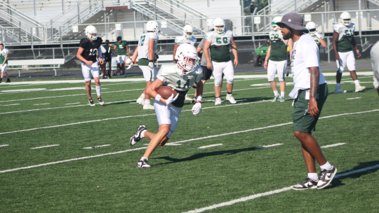 Ducks varsity football senior wide receiver Jordan Pickerill catches the ball and makes a move up field as Taylor assistant coach Xavier Johnson watches on Wednesday during practice.